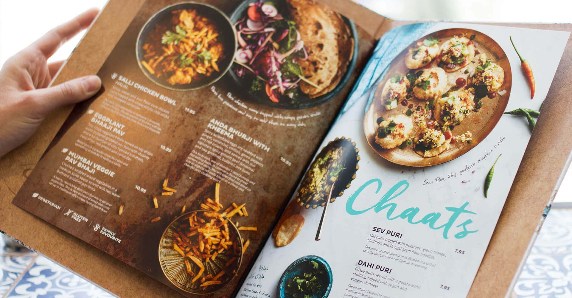 A person is holding a menu with a variety of food on it.