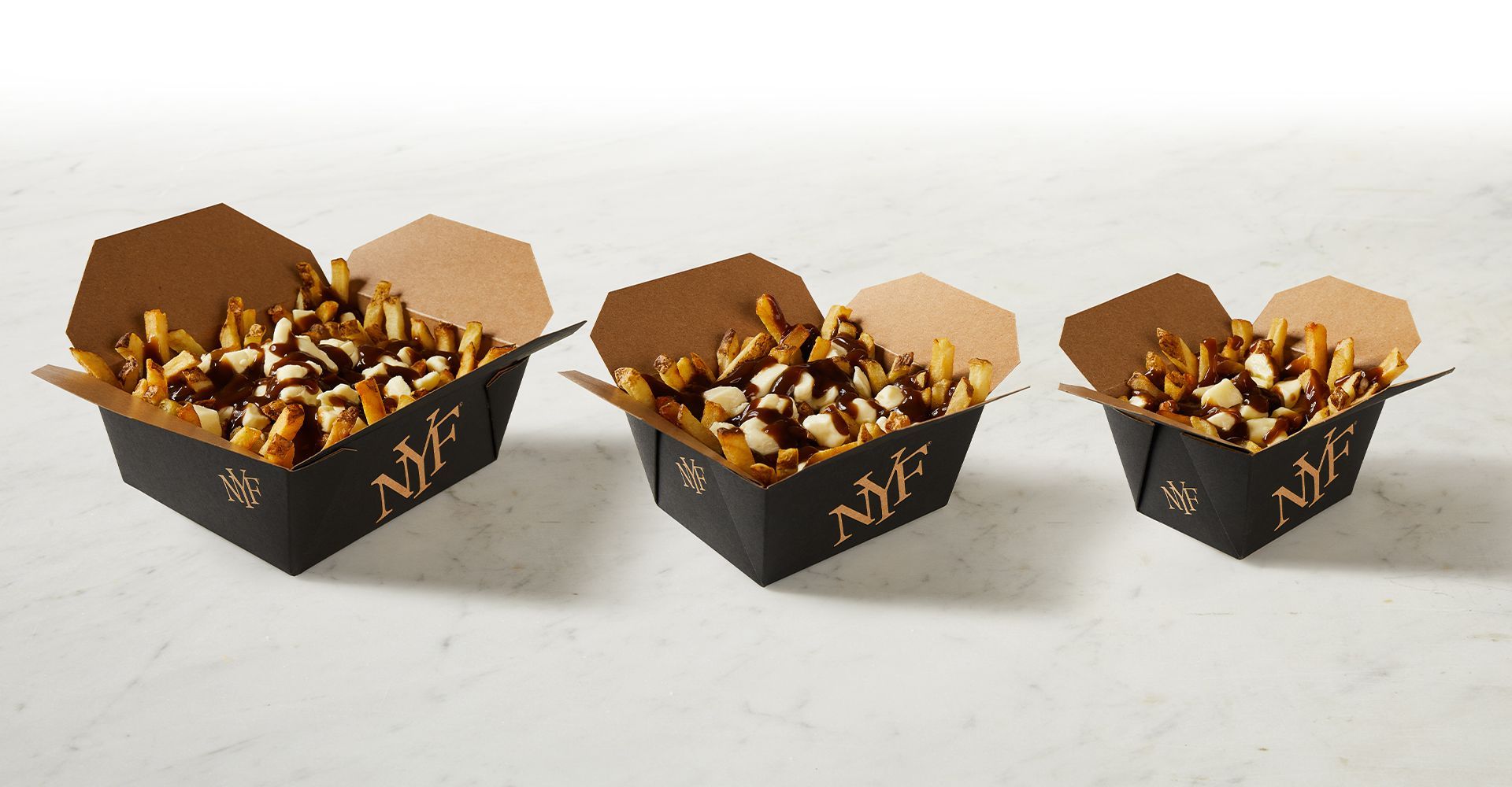 Three boxes of french fries are sitting on a table.