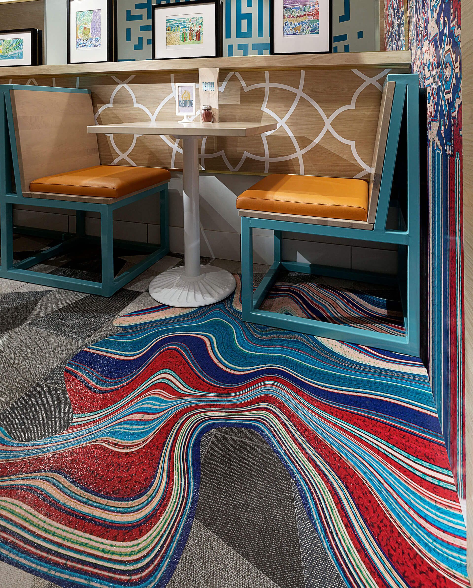 A restaurant with a table and chairs and a colorful rug on the floor.