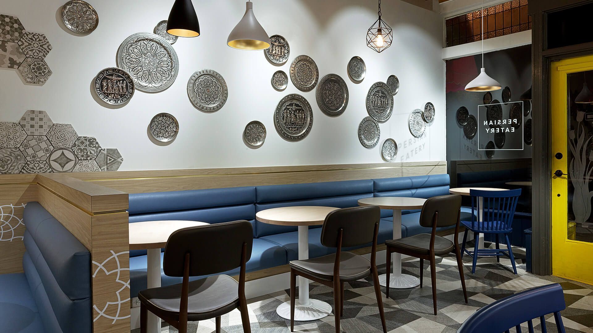 A restaurant with tables and chairs and plates on the wall