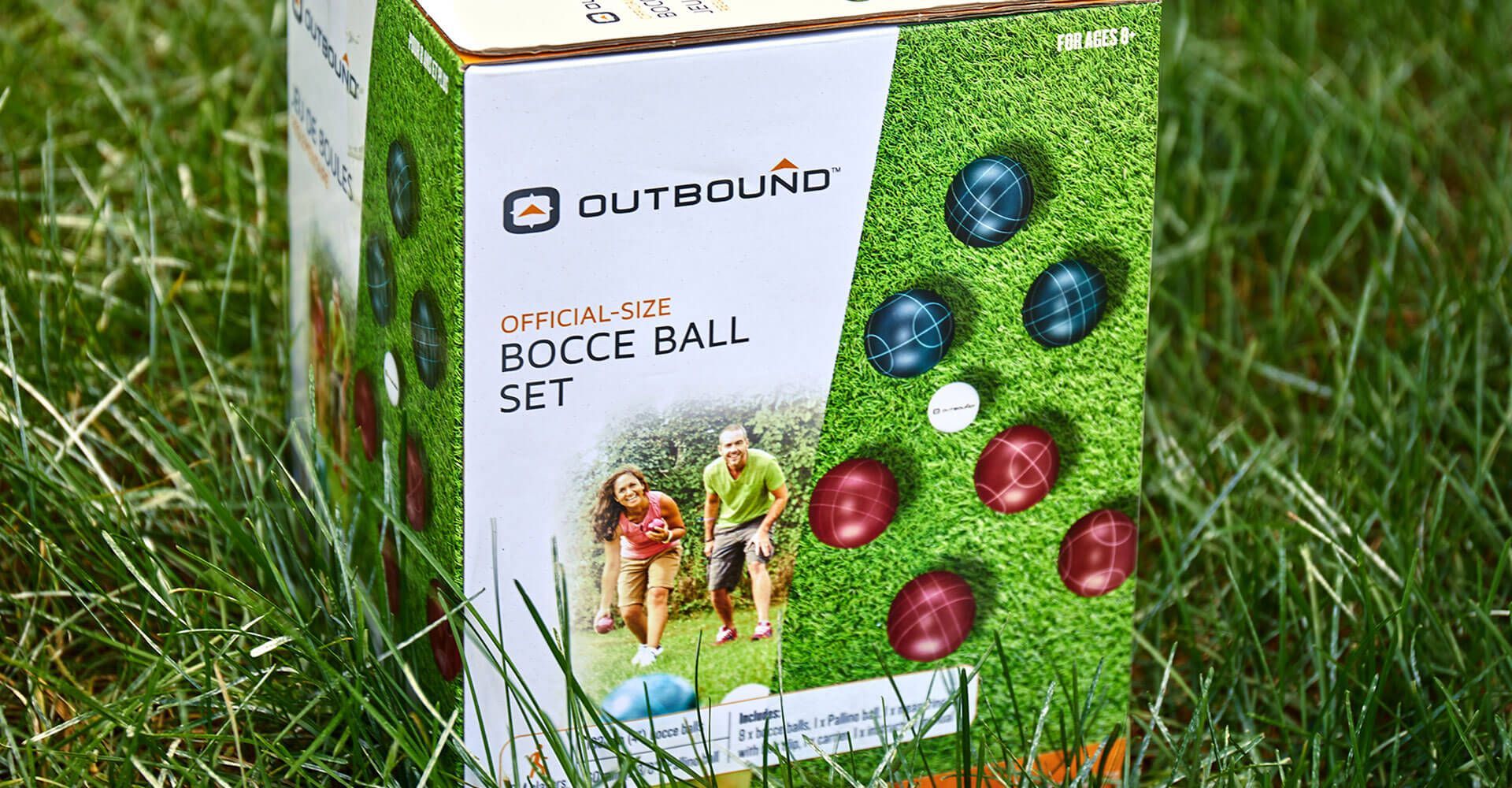 A box of bocce balls is sitting in the grass.