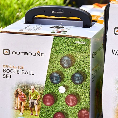 A box of bocce balls is sitting on top of a lush green field.