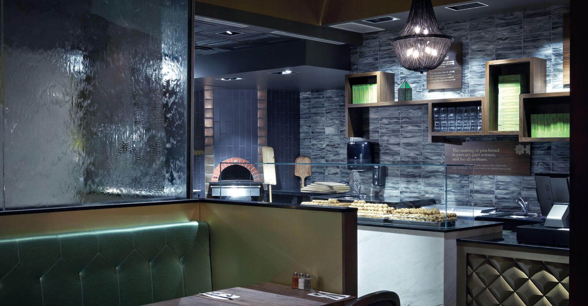 A restaurant with a green bench and a glass wall