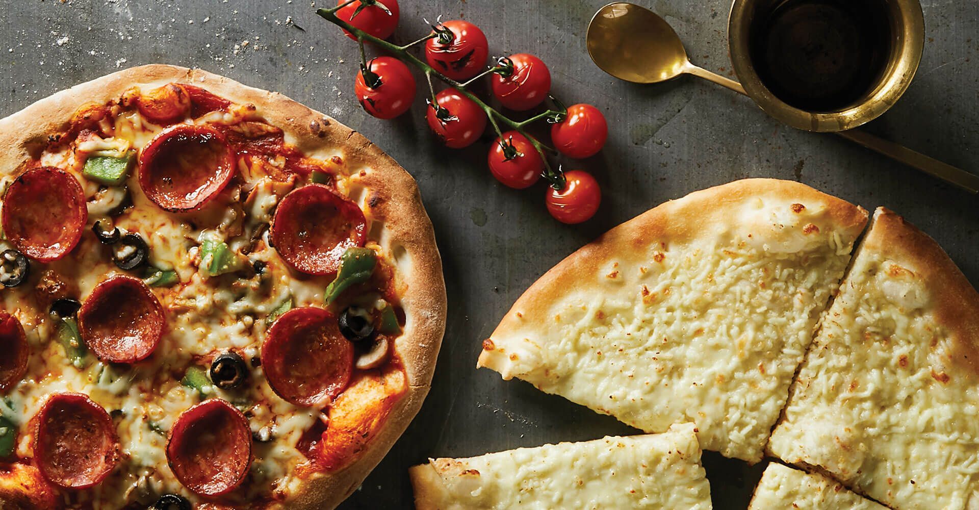 A pepperoni pizza and a white pizza are on a table.