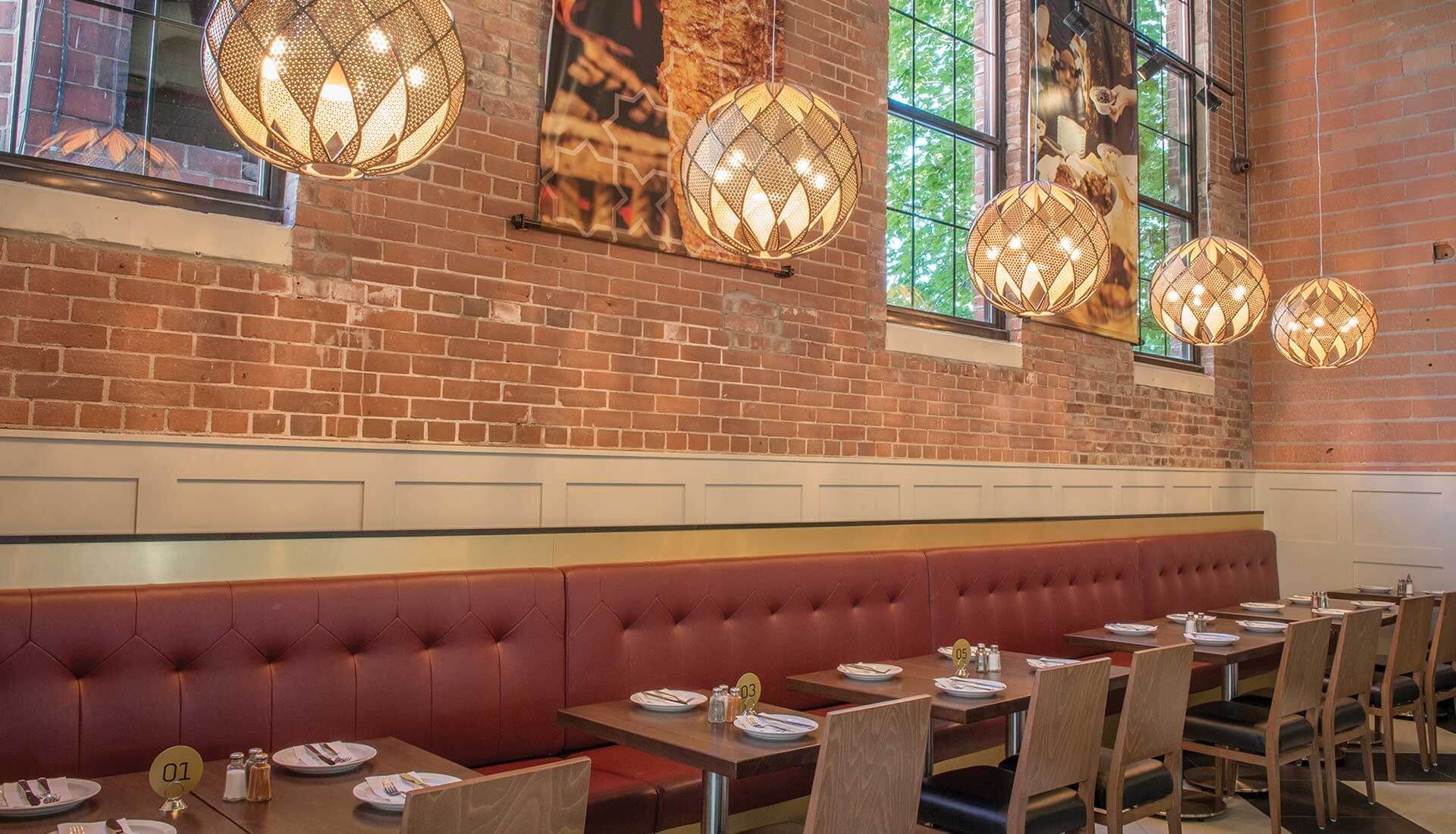 A restaurant with tables and chairs and a brick wall.