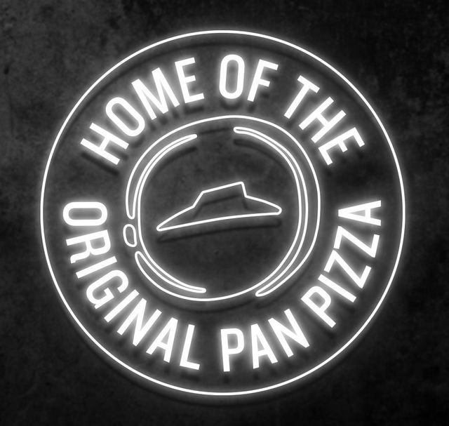 A neon sign that says home of the original pan pizza