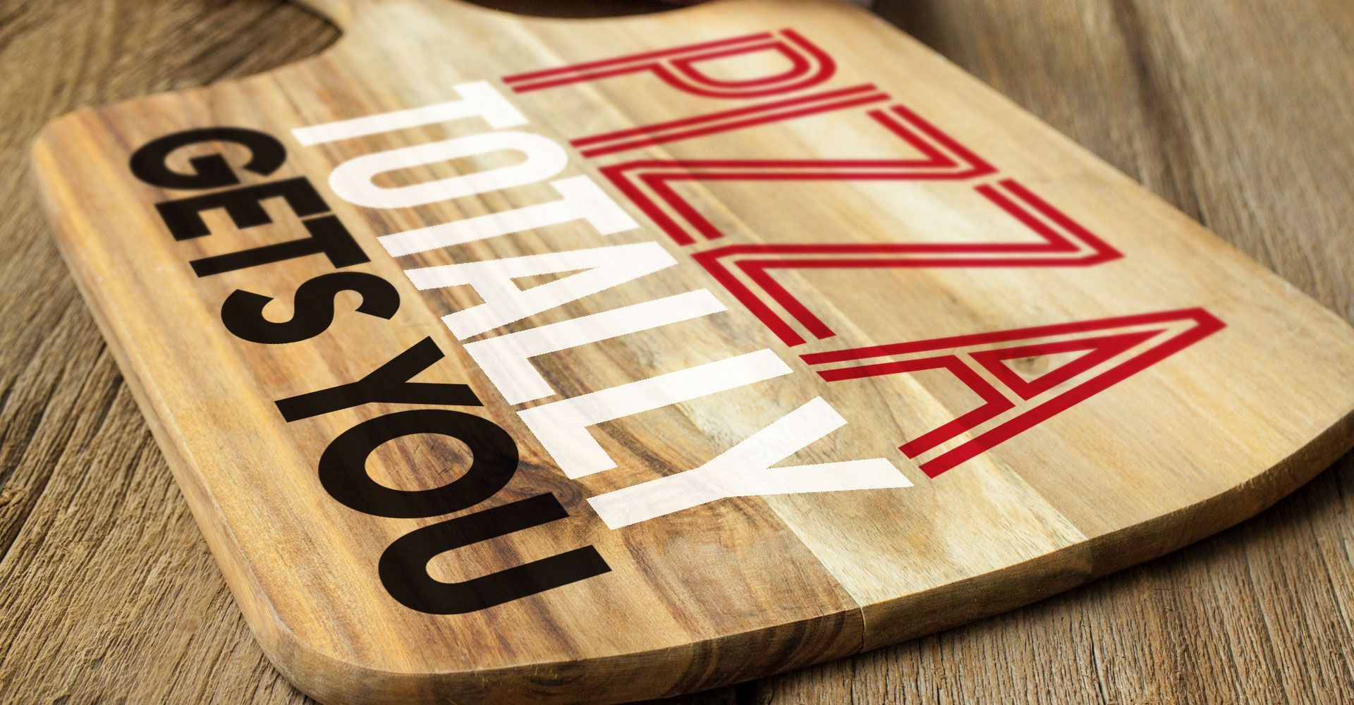 A wooden cutting board that says pizza totally gets you