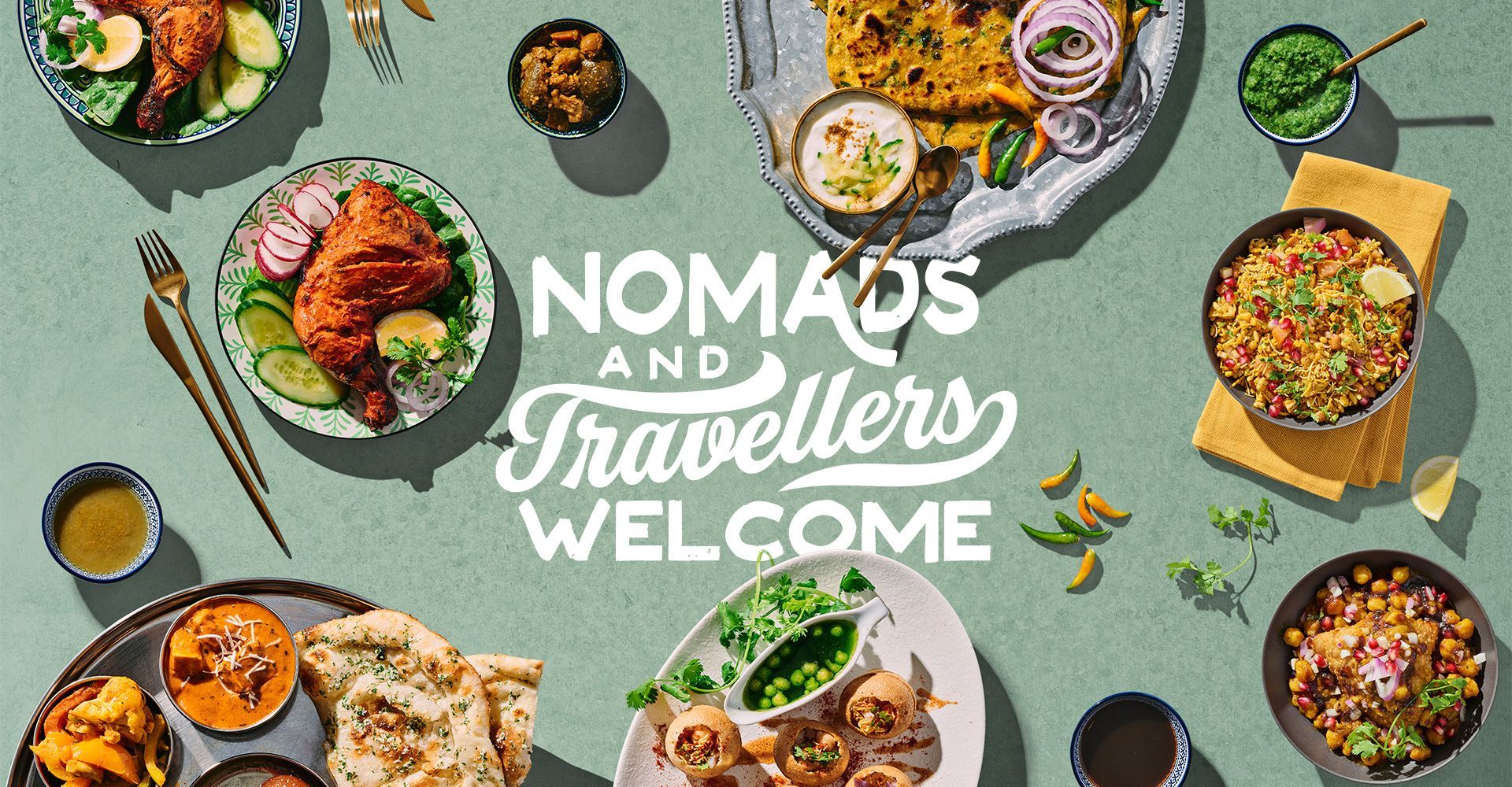 A table topped with plates of food and the words nomads and travellers welcome.