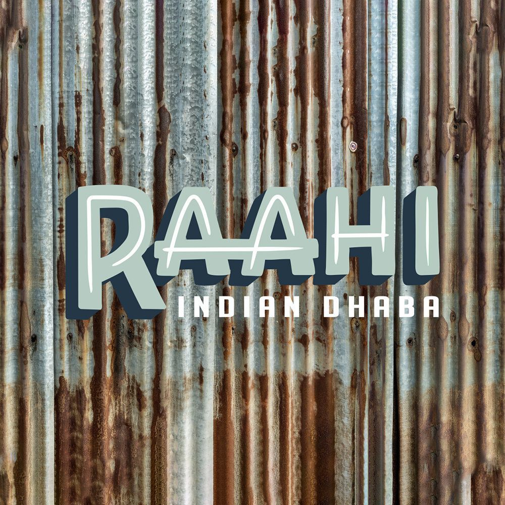 The logo for raahi indian dhaba is on a rusty metal wall.