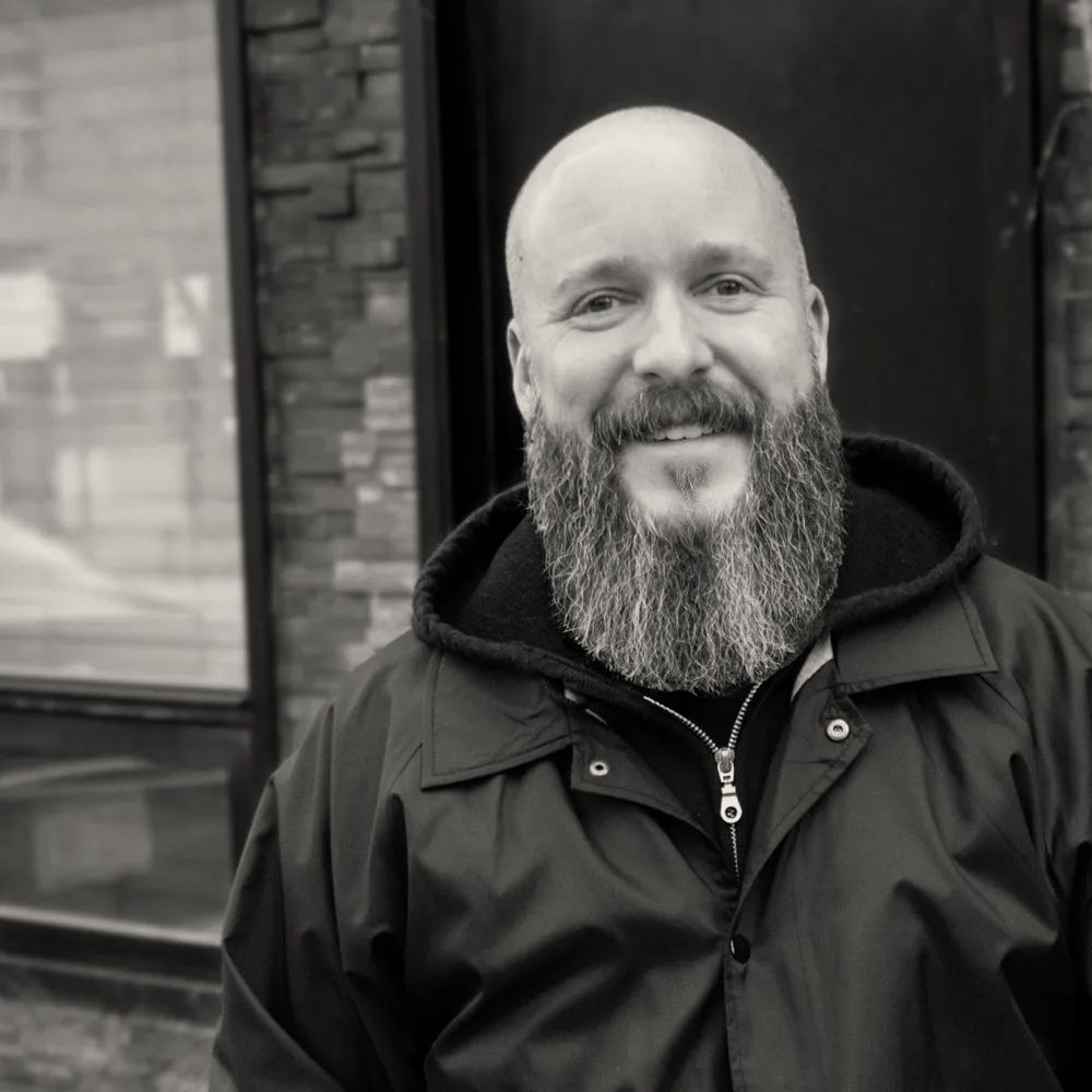 A bald man with a beard wearing a black jacket