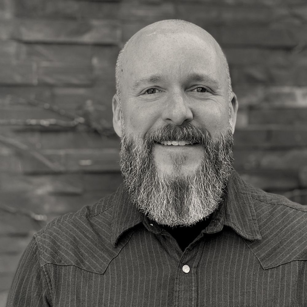 A bald man with a beard wearing a black jacket