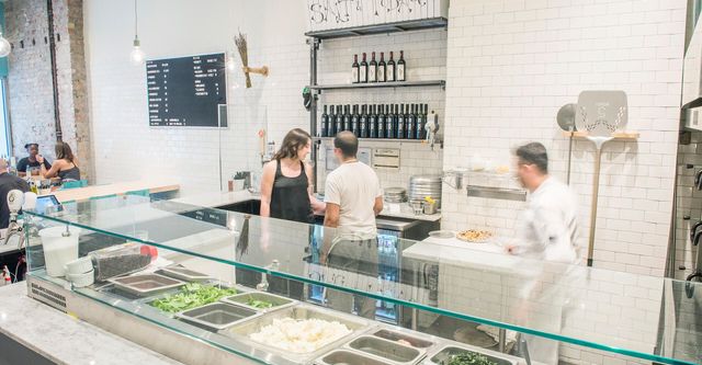 A blurry picture of a restaurant with people standing behind a glass counter.