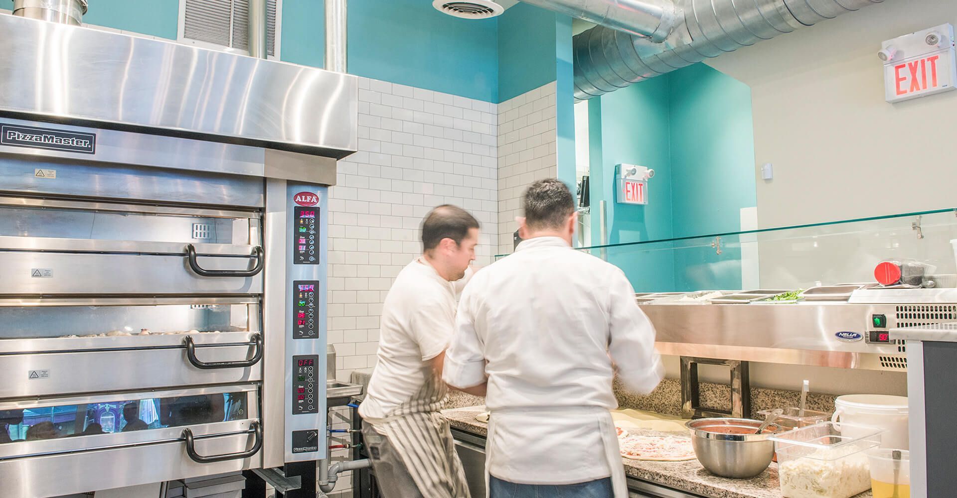 Two men are standing in a kitchen in front of an oven.