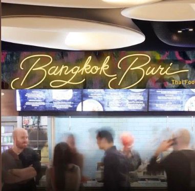 A blurred image of people standing in front of a sign that says bangkok buri