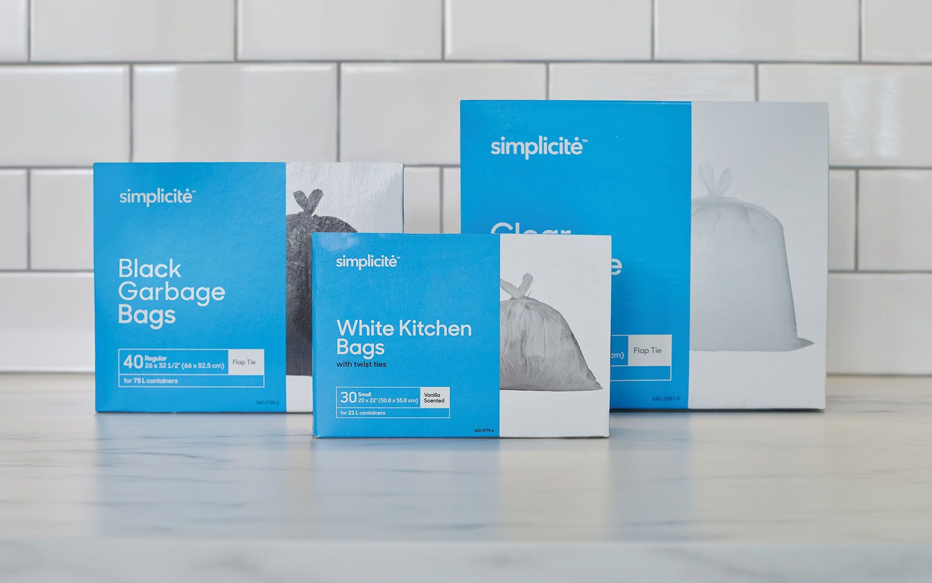 Three boxes of garbage bags are sitting on a counter.