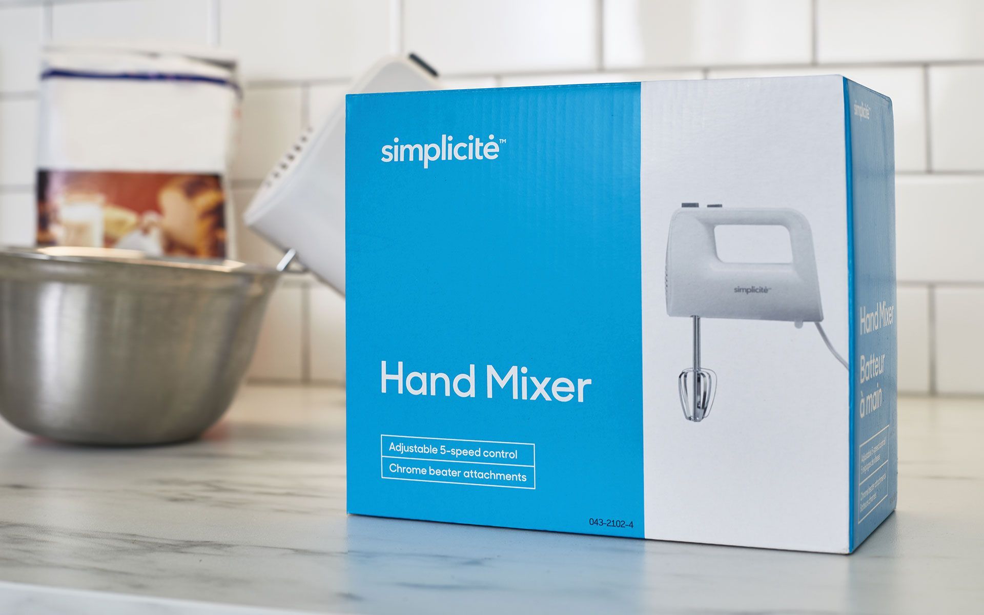 A hand mixer is sitting on a counter next to a bowl.