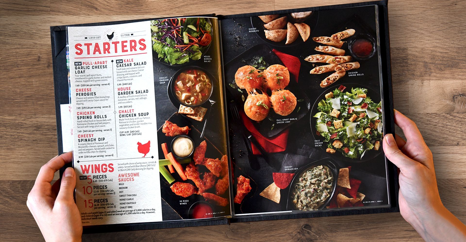 A person is holding a menu with starters and wings on it.