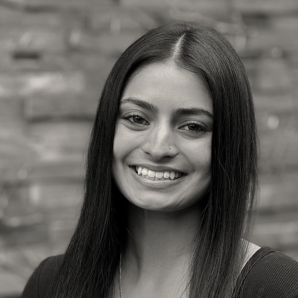 A woman in a white sweater is smiling in a black and white photo.