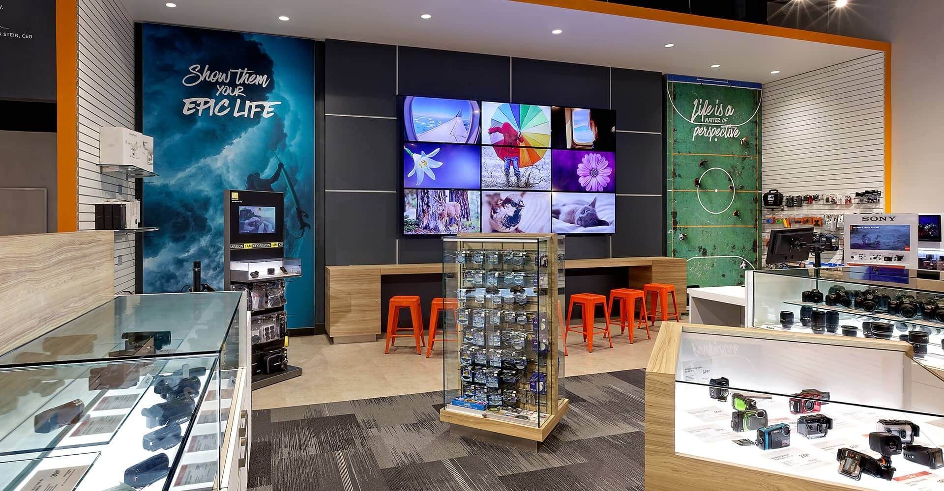 A store filled with lots of cameras and a large screen.