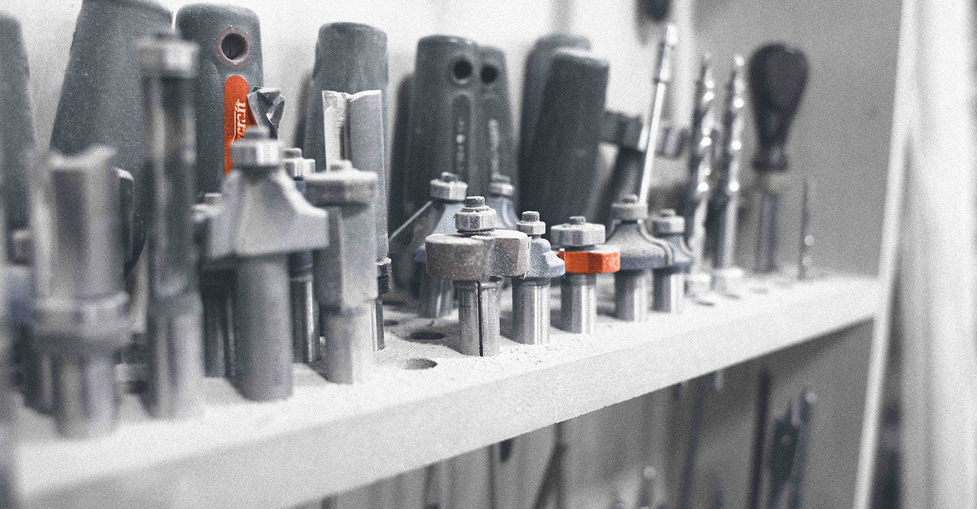 A bunch of tools are lined up on a shelf.