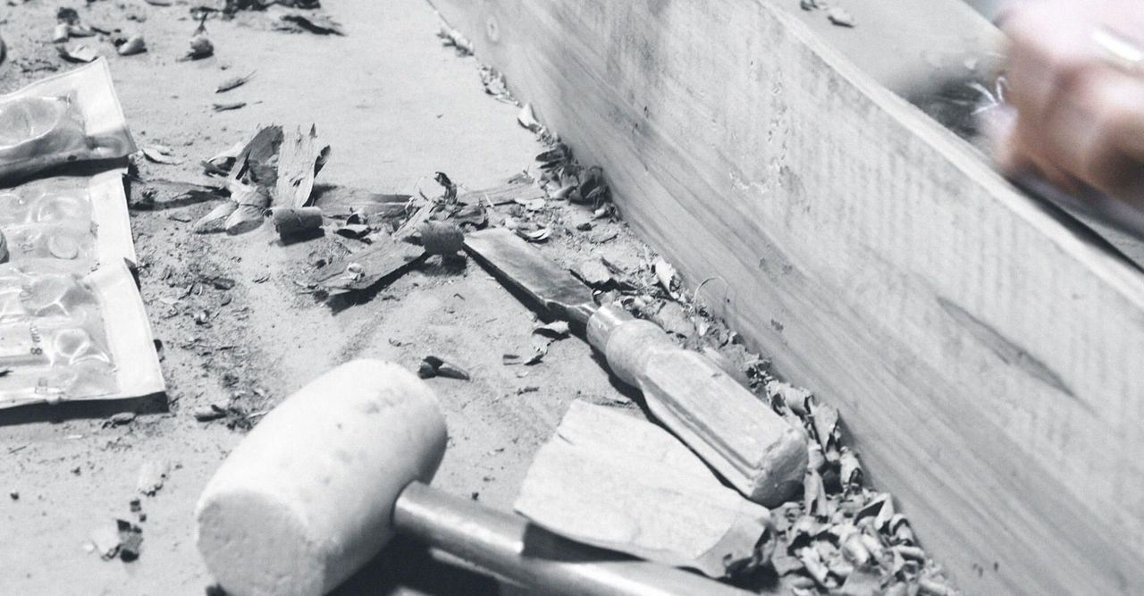 A black and white photo of a person carving a piece of wood