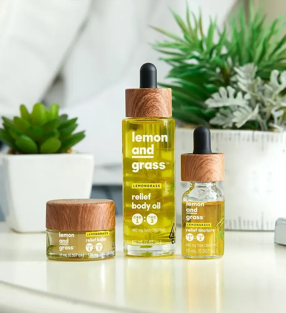 Three bottles of lemon and grass relief body oil are sitting on a table.