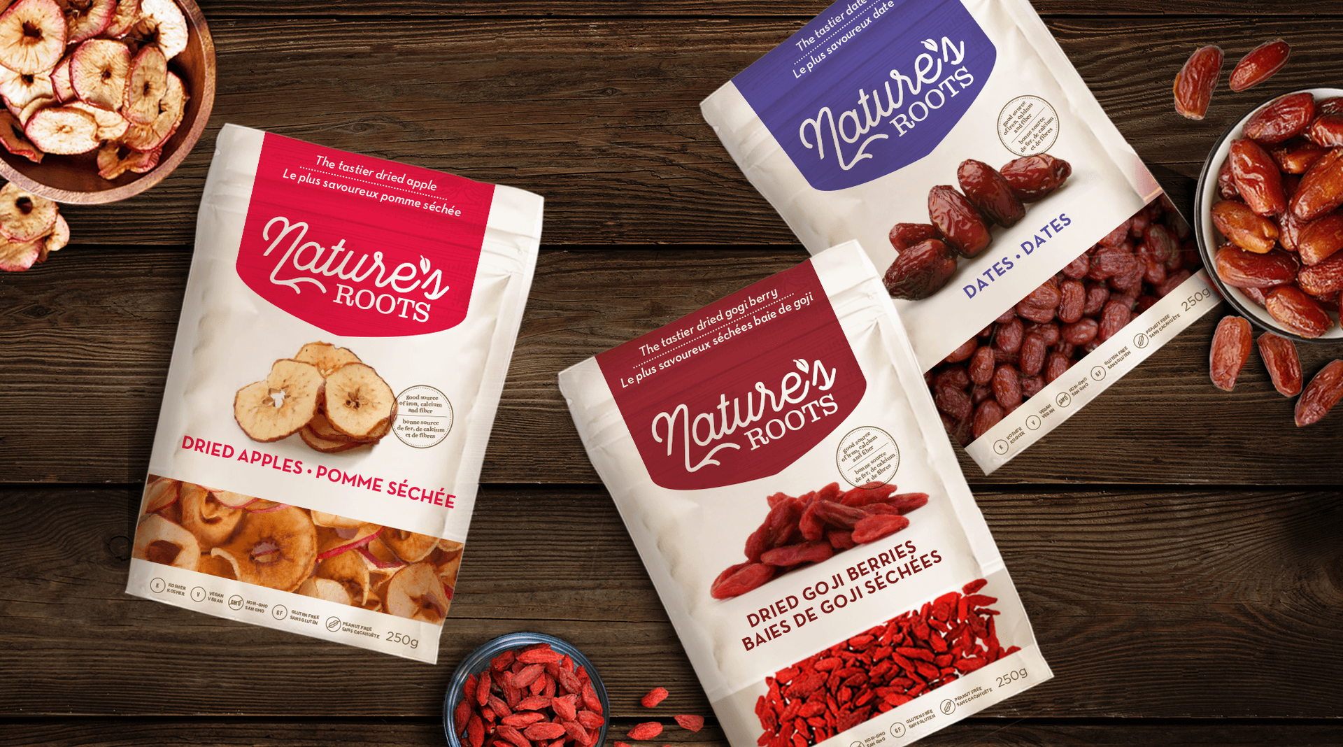 Three bags of dried fruits are sitting on a wooden table.