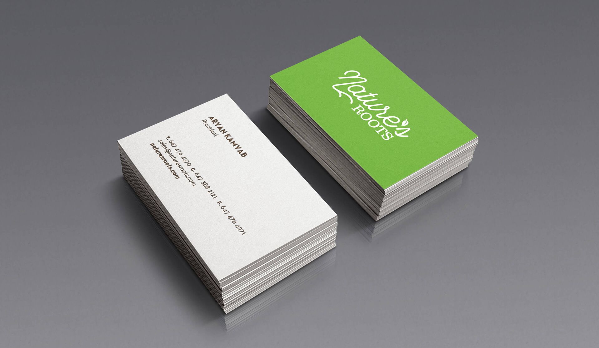 Two business cards are stacked on top of each other on a table.