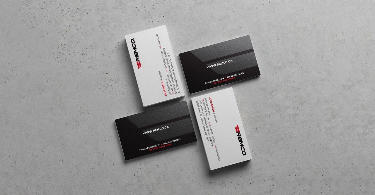 Three business cards are stacked on top of each other on a concrete surface.