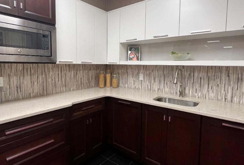 Modern kitchen with white and dark brown cabinets, stainless steel appliances, and a tiled backsplash.