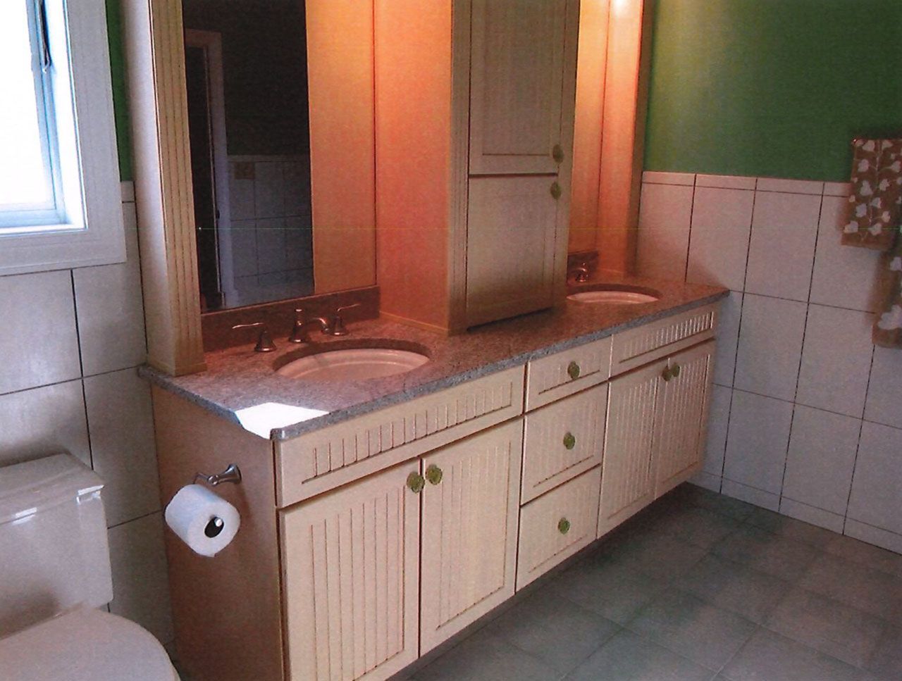 Bathroom with light wood cabinets, double sinks, and a large mirror.