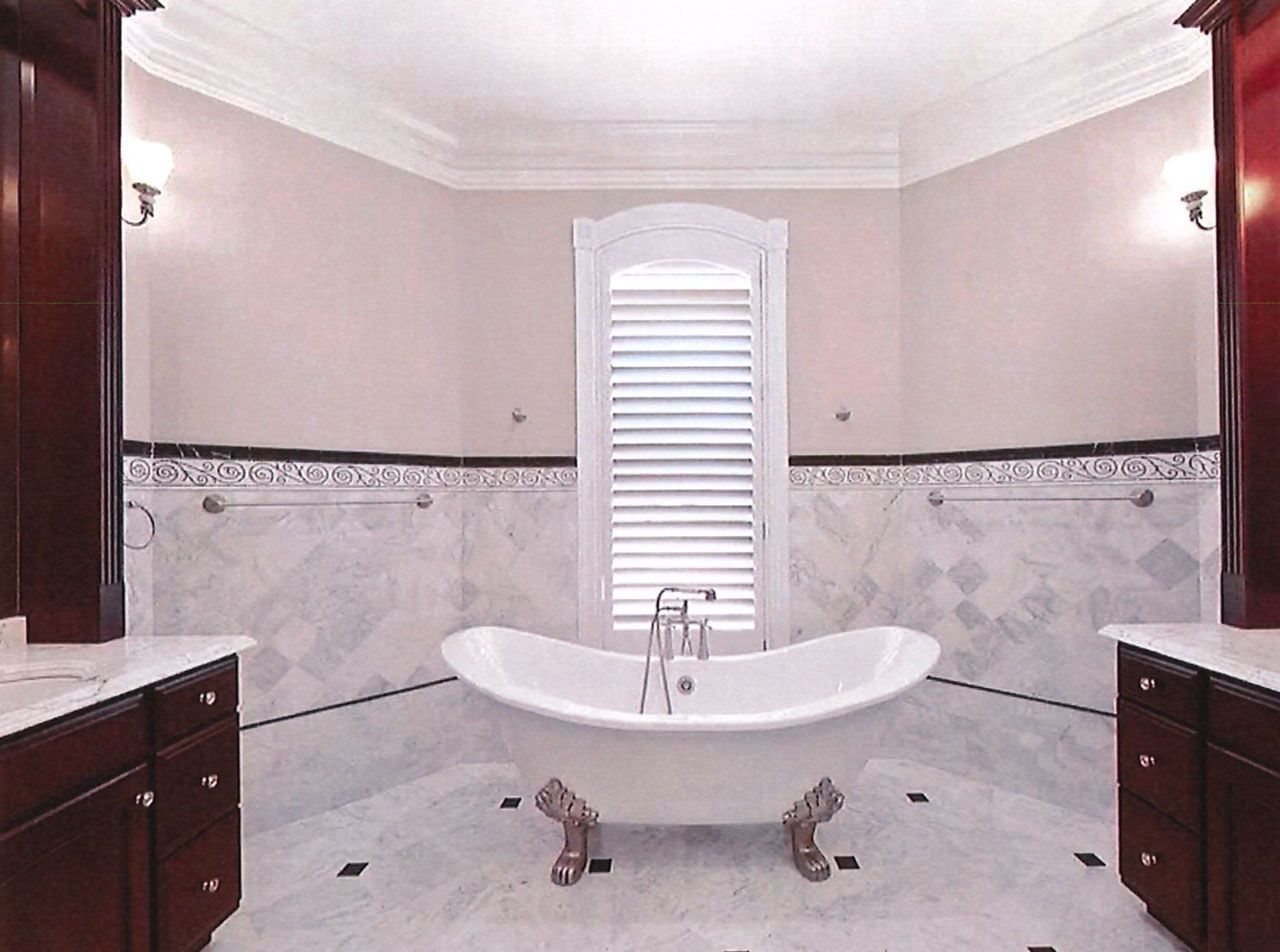 Luxurious bathroom with clawfoot tub, marble tiles, and dark wood cabinets.