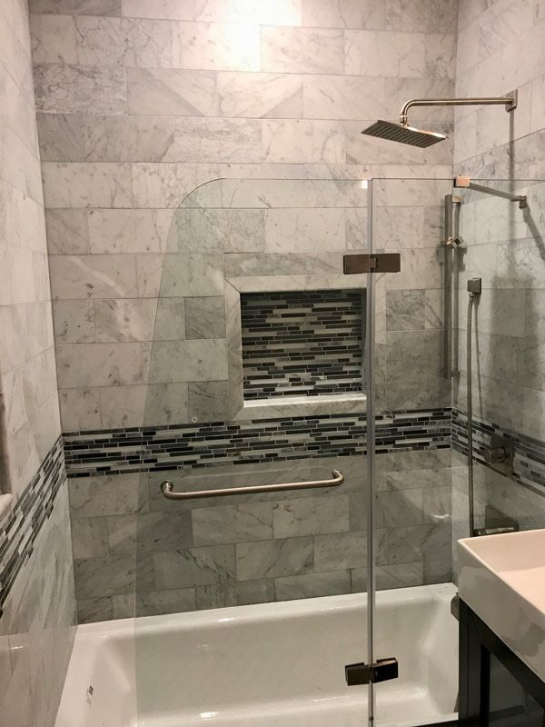 Bathroom with marble tile walls, a glass shower door, and a built-in shelf.