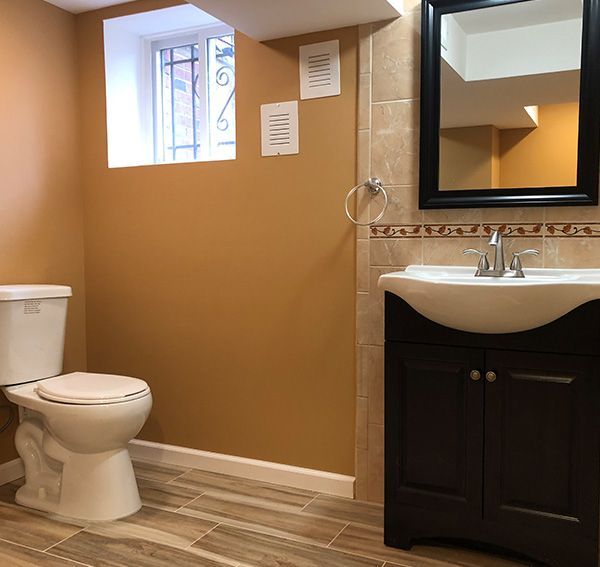 Bathroom with toilet, vanity, window, and brown walls and floor.