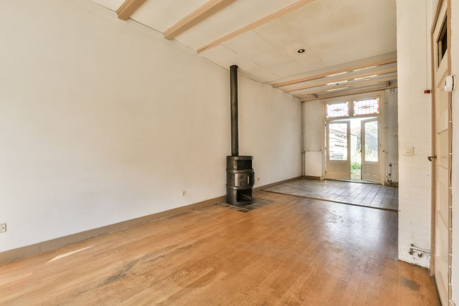 Empty room with hardwood floors, a fireplace, and doors leading outside.