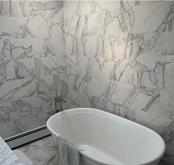 White clawfoot bathtub against marble tile wall.