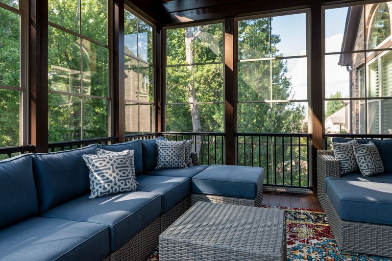 Blue sectional seating in a screened porch with a view of trees.