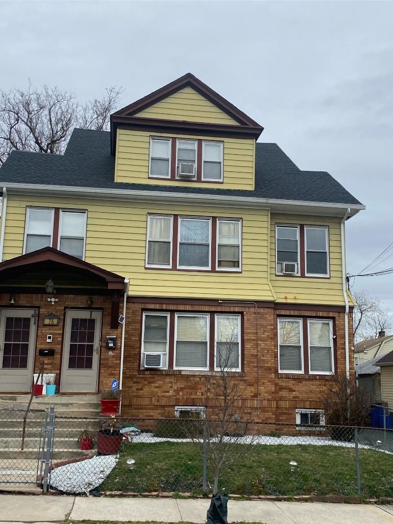 Two-story yellow and brown building with multiple windows; overcast sky.