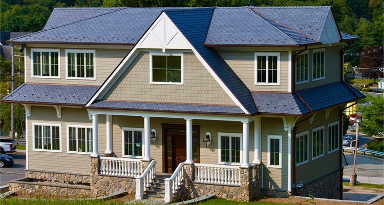 Two-story beige house with a stone porch, windows, and gray roof.