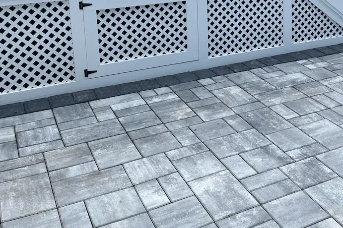 Gray paver patio with white lattice fence.
