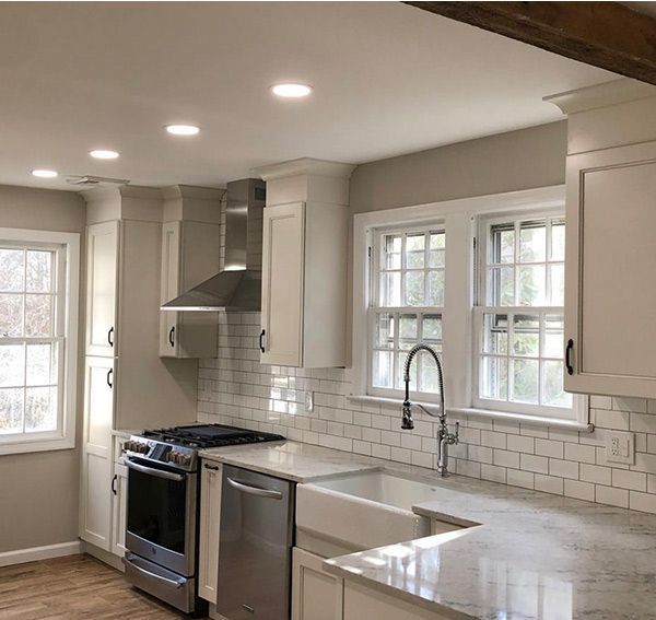 Newly renovated white kitchen with stainless steel appliances and subway tile backsplash.