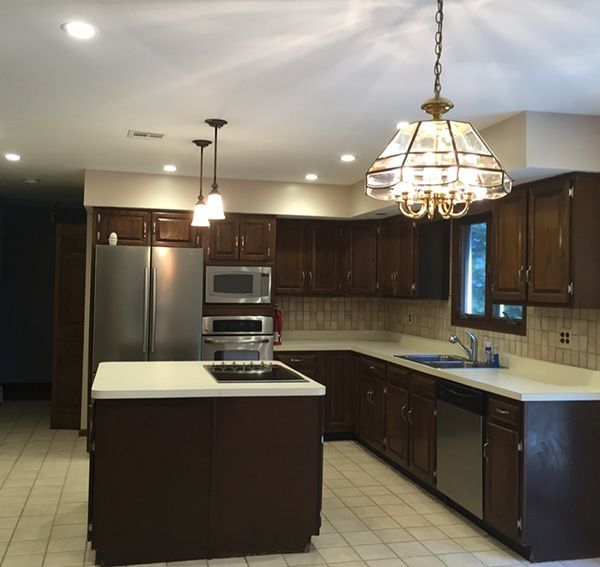 A kitchen with dark wood cabinets, stainless steel appliances, and a central island with a stovetop.