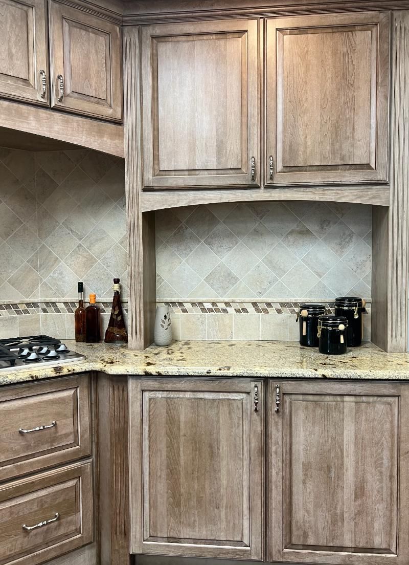Kitchen with light brown wood cabinets, granite countertops, and tiled backsplash.