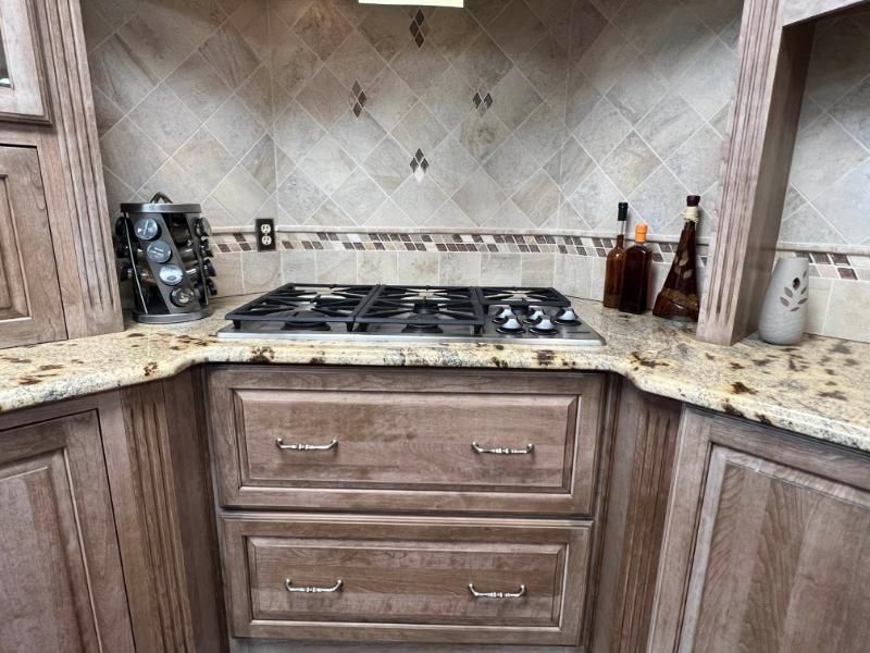 Kitchen with a stovetop, drawers, and tile backsplash.