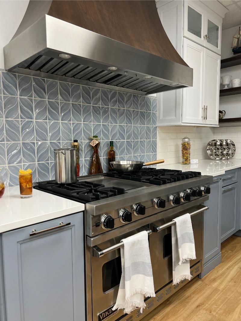 Kitchen with stainless steel range, blue tile backsplash, and light blue cabinets.