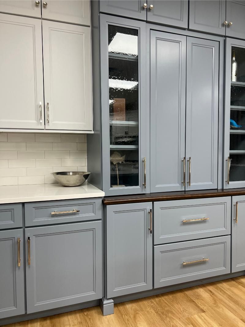 Gray and white kitchen cabinets with glass-front display cabinets.