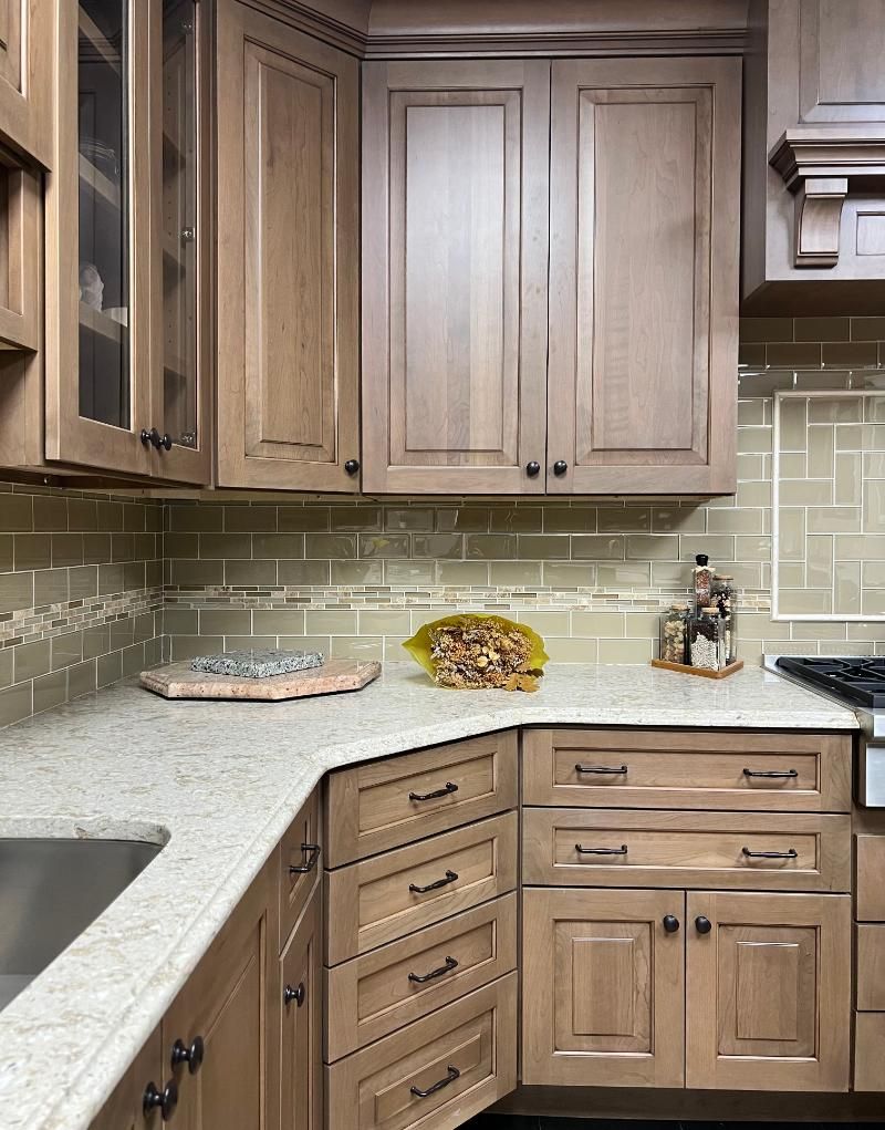 Kitchen cabinets in shades of beige and brown, with light-colored countertops and a tiled backsplash.