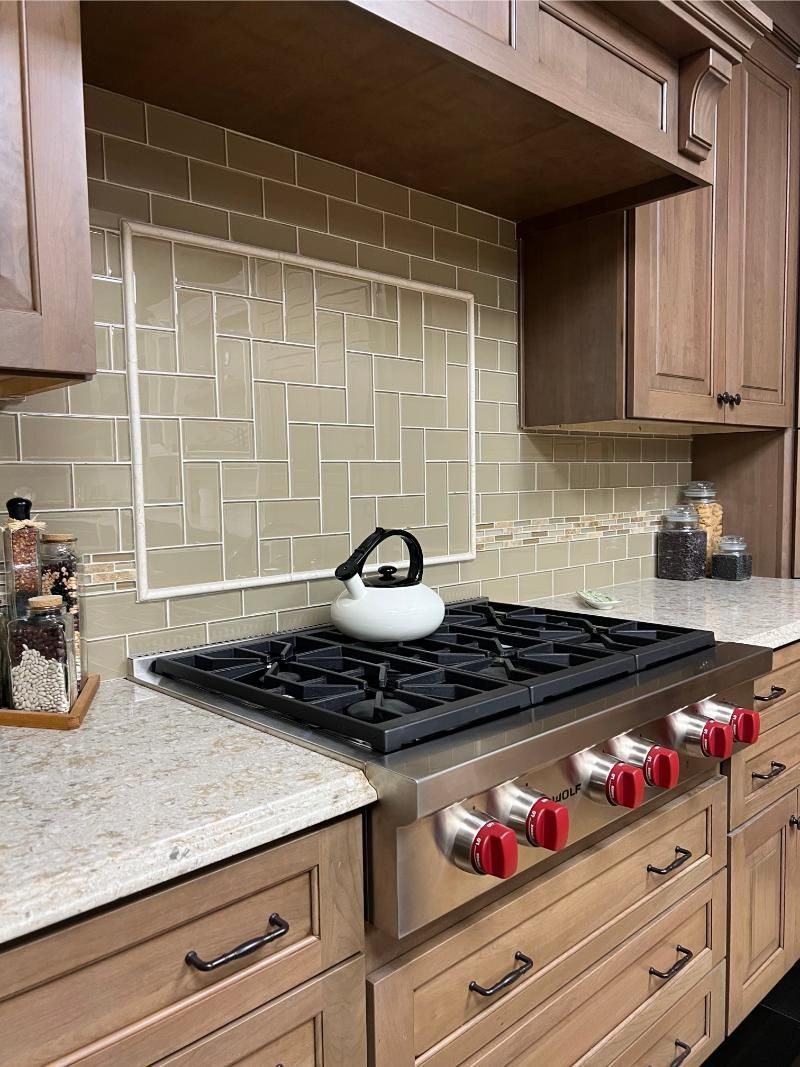 Kitchen with a gas stovetop, tile backsplash, wooden cabinets, and a kettle.