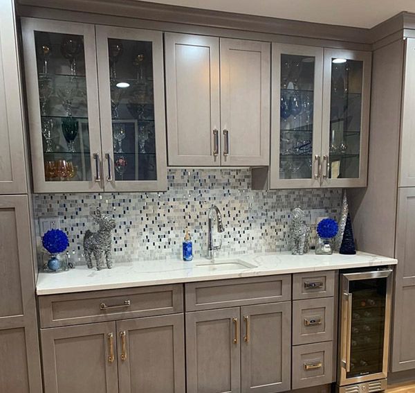 Gray kitchen cabinets with glass-front uppers, a tiled backsplash, and a wine fridge.