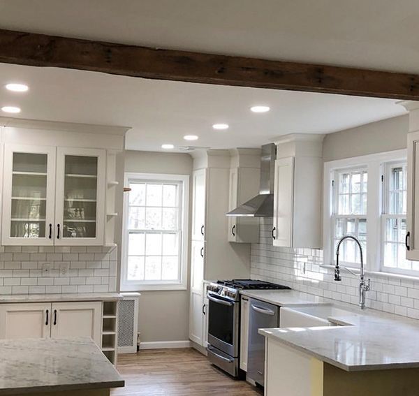 Kitchen with white cabinets, stainless steel appliances, and a wooden beam.